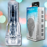 A transparent male pocket toy, the Fleshlight GO Torque Portable Stroker Toy from Fleshlight, with various texture patterns is shown next to its packaging box. The box features an image of the product, branding, and key features like ease of cleaning and storage. Perfectly designed for portable convenience, it’s your ideal travel buddy. The background is a soft focus of colorful light spots.